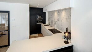 A modern kitchen with a marble backsplash, built-in appliances, and a minimalist design. - Apartment in Seaside Bliss (Knokke-Heist)