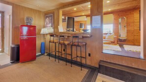Un interno in legno con un frigorifero rosso, sgabelli da bar e un'ampia finestra.