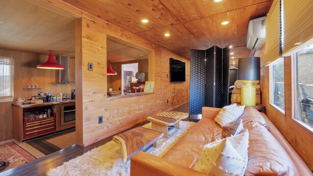 L'interno accogliente di una baita con soffitto in legno, un divano, un'area pranzo e una cucina.