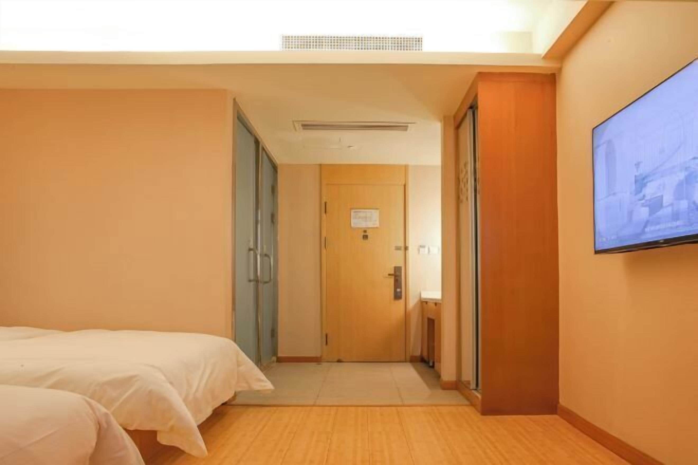 A hotel room with a bed, a television, and a door leading to another room.