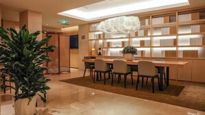 A modern library with a high ceiling, bookshelves, a dining area, and a large potted plant. - Meihao EZZI Hotel (Tianjin Youyi Road Wudadao) (Tianjin)