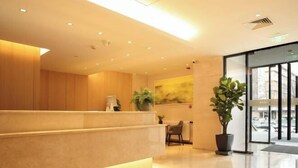A modern reception area with a marble counter, potted plants, and a large window offering a view of the street. - Meihao EZZI Hotel (Tianjin Youyi Road Wudadao) (Tianjin)