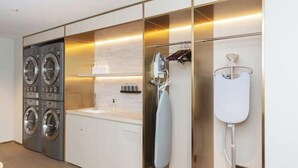 A modern laundry room with two front-loading washing machines, a sink, and a hairdryer. - Meihao EZZI Hotel (Tianjin Youyi Road Wudadao) (Tianjin)