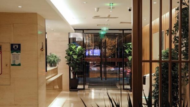 A hotel lobby with a reception desk, potted plants, and a glass door leading to the entrance. - Meihao EZZI Hotel (Tianjin Youyi Road Wudadao) (Tianjin)