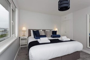 Et hotelværelse med en stor seng, to sengeborde, et skab og et vindue med udsigt.