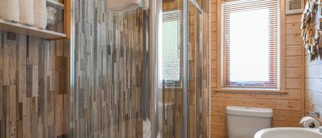 A wooden cabin bathroom with a shower, toilet, and sink.