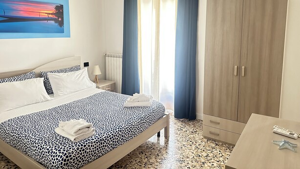 A hotel room with a bed, a nightstand, a lamp, a wardrobe, and a painting on the wall. - b&b stella in centro (Salerno)
