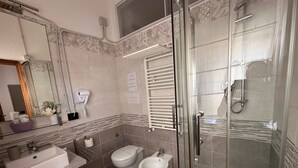 A modern bathroom with a glass-enclosed shower, two toilets, a sink, and a mirror. - b&b stella in centro (Salerno)
