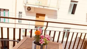A wooden table with a potted plant on a balcony with tiled flooring and metal railings. - b&b stella in centro (Salerno)