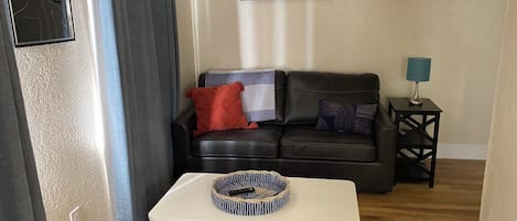 Relax in this stylish living room with a black leather sofa, coffee table, and abstract art piece.