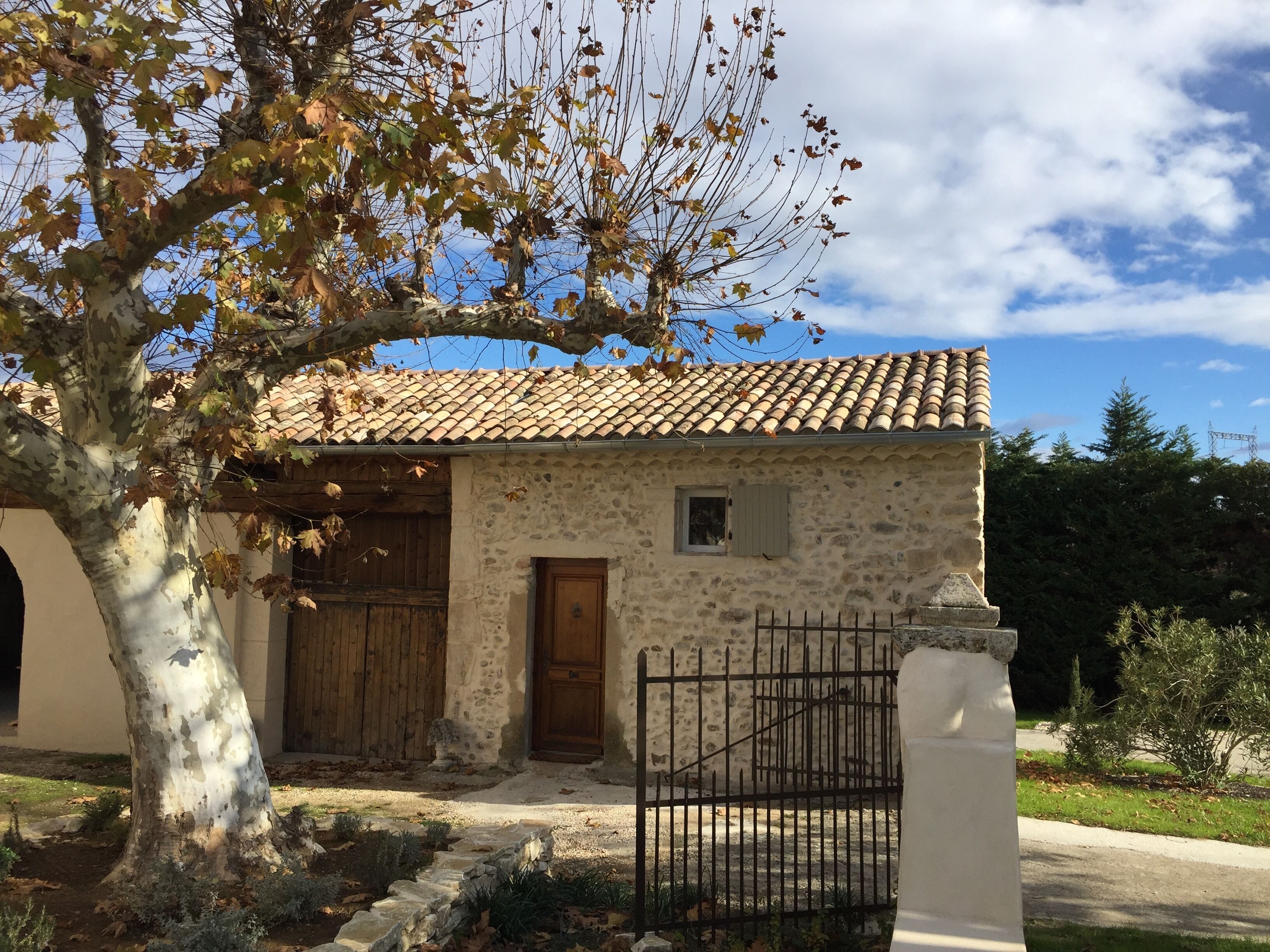 Un edificio de piedra con techo de tejas, una puerta de madera y un portón de metal.