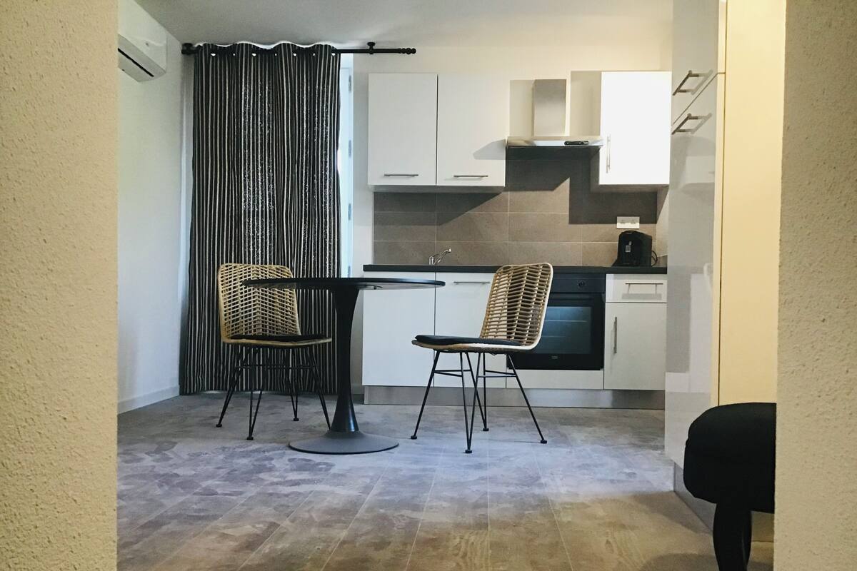 A compact kitchen with two chairs, a dining table, and a kitchen island.