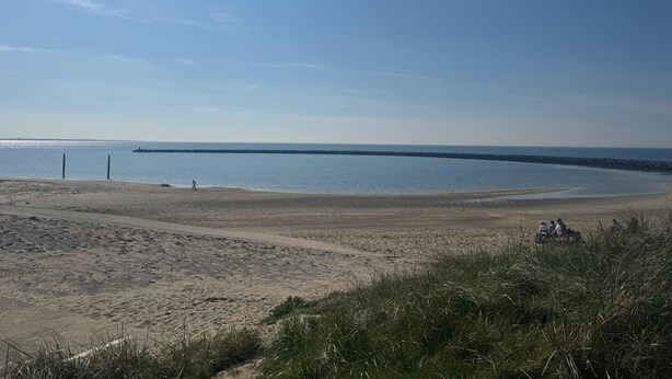 A beach with a clear sky, calm water, and a distant pier. - Villa Frans -Gezellige bungalow in Renesse (Renesse)