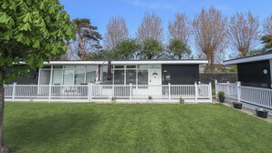 Un bâtiment moderne, avec une clôture blanche, une pelouse verdoyante et des arbres en arrière-plan.