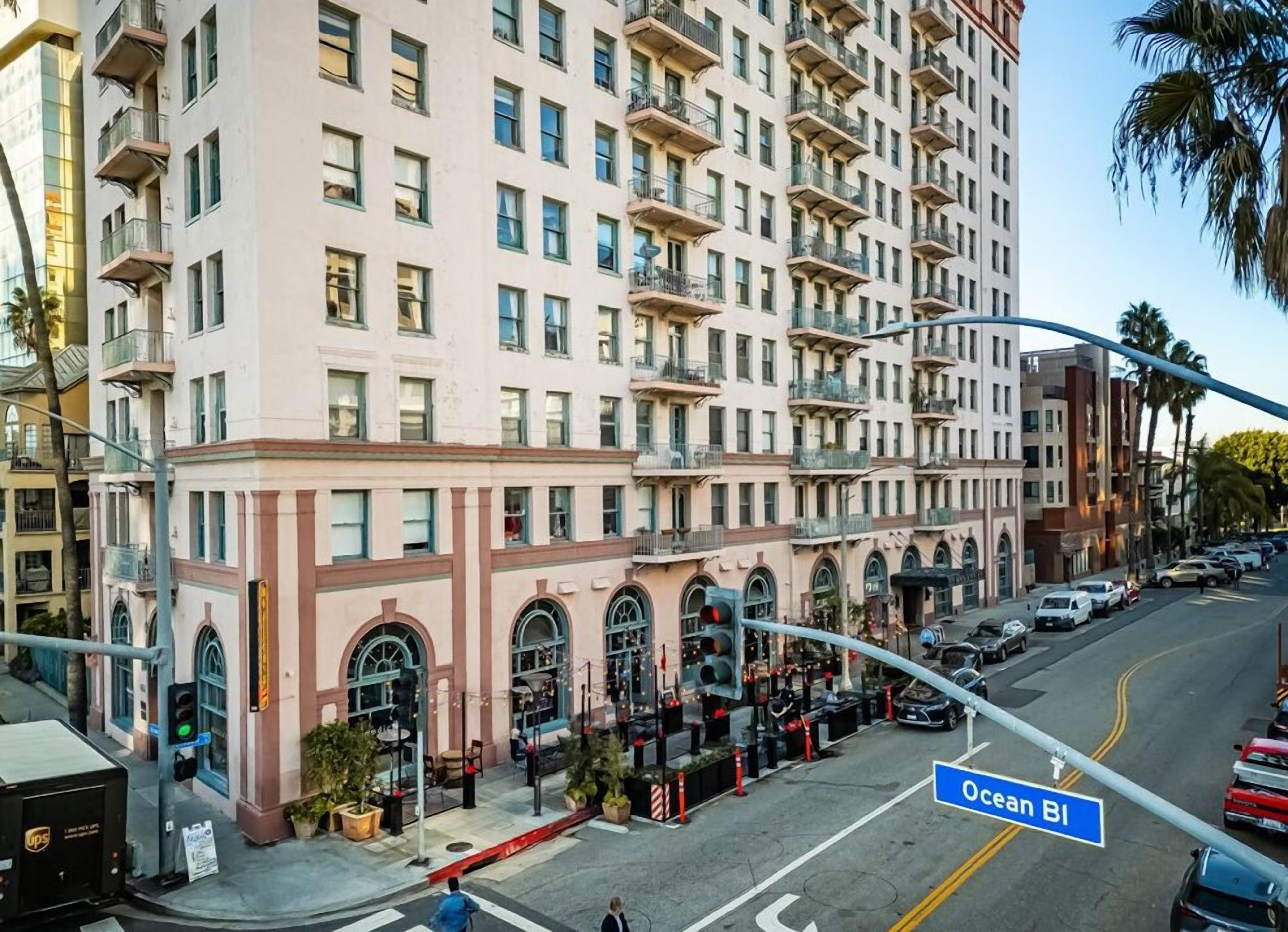 A multi-story hotel with balconies, a ground-level restaurant with outdoor seating, and a street view with cars and a UPS delivery truck.