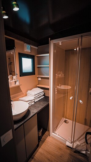 A compact bathroom with a sink, towel stack, and a glass shower enclosure. - Hotel Chalet Montegut (Coulandon)
