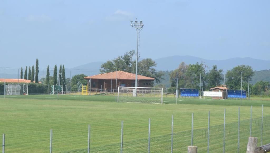 A soccer field with goalposts, a covered seating area, and a tall floodlight structure.