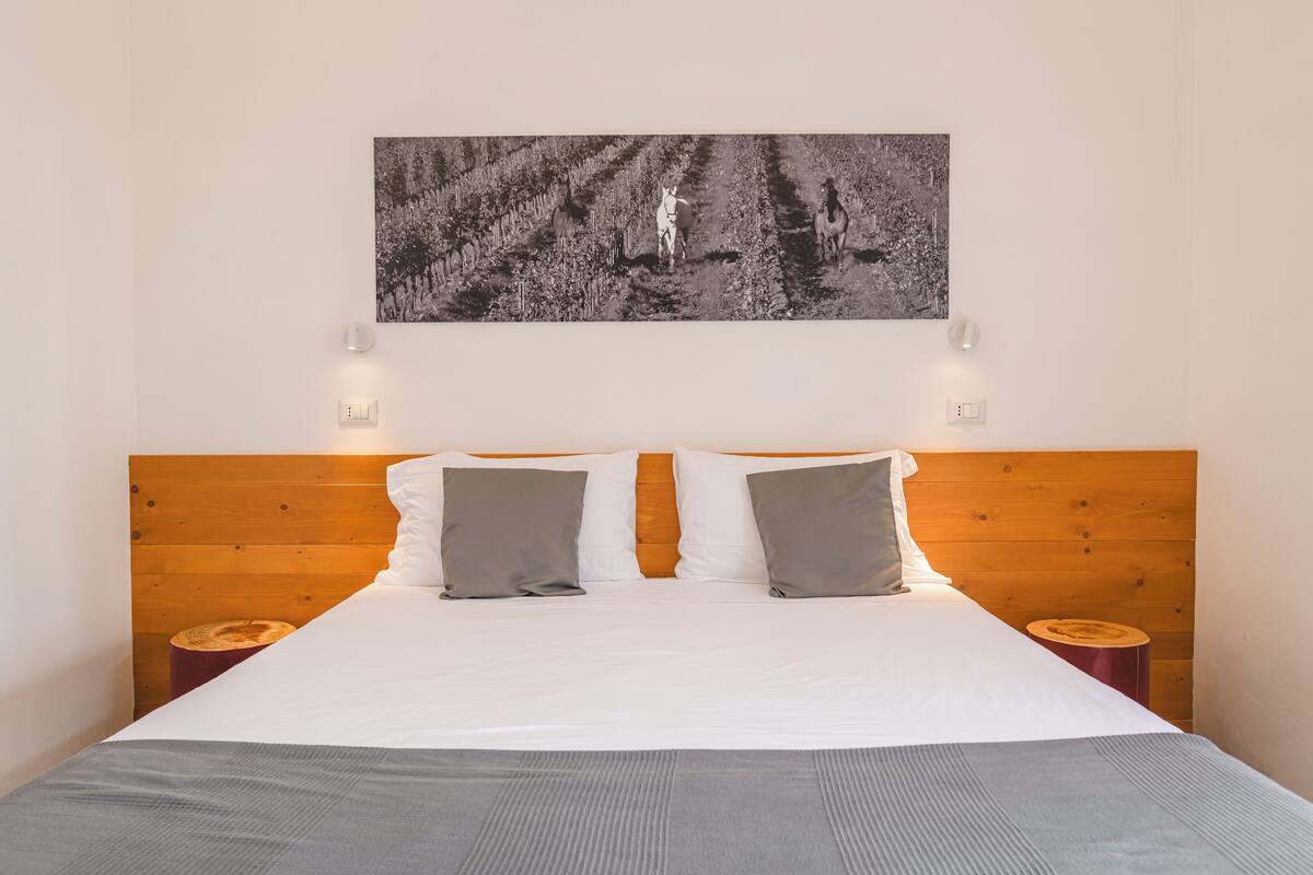 A neatly made bed with a wooden headboard, two bedside tables, and a black and white photograph above the bed.