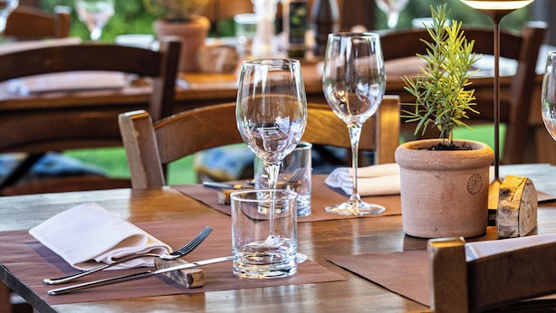 A dining table set with wine glasses, a candle, and a small potted plant.