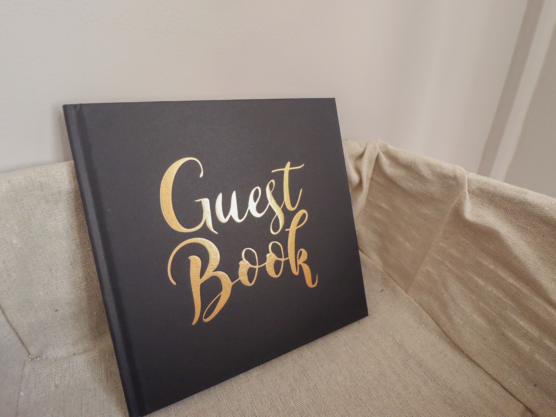 A black book titled "Guest Book" on a beige couch.