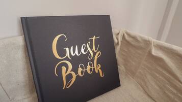 A black book titled "Guest Book" on a beige couch.