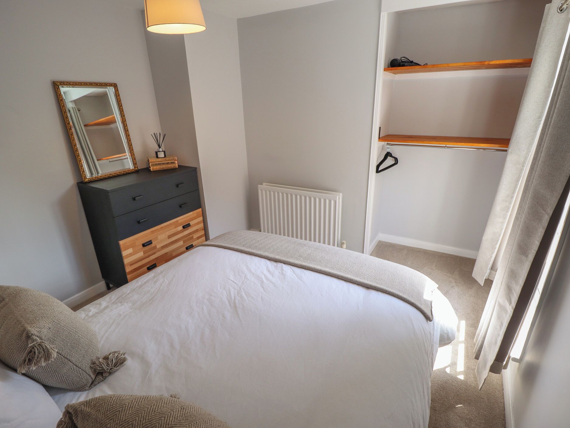 Une chambre à coucher avec un lit, une commode, un miroir et un radiateur.