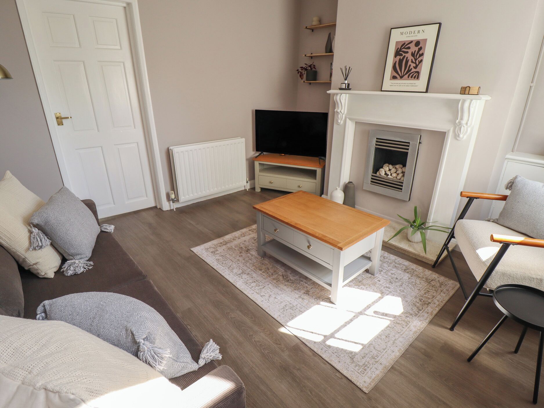 A living room with a sofa, a coffee table, a TV, a fireplace, and a bookshelf.