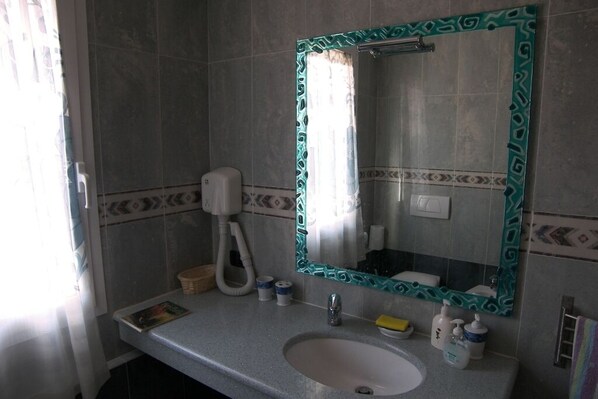 A bathroom with a sink, mirror, and hand dryer.
