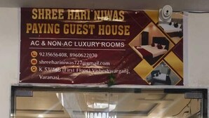A glass door entrance to a guest house with a sign above advertising AC & NON-AC luxury rooms. - Shree Hari Niwas Paying Guest House (Varanasi)