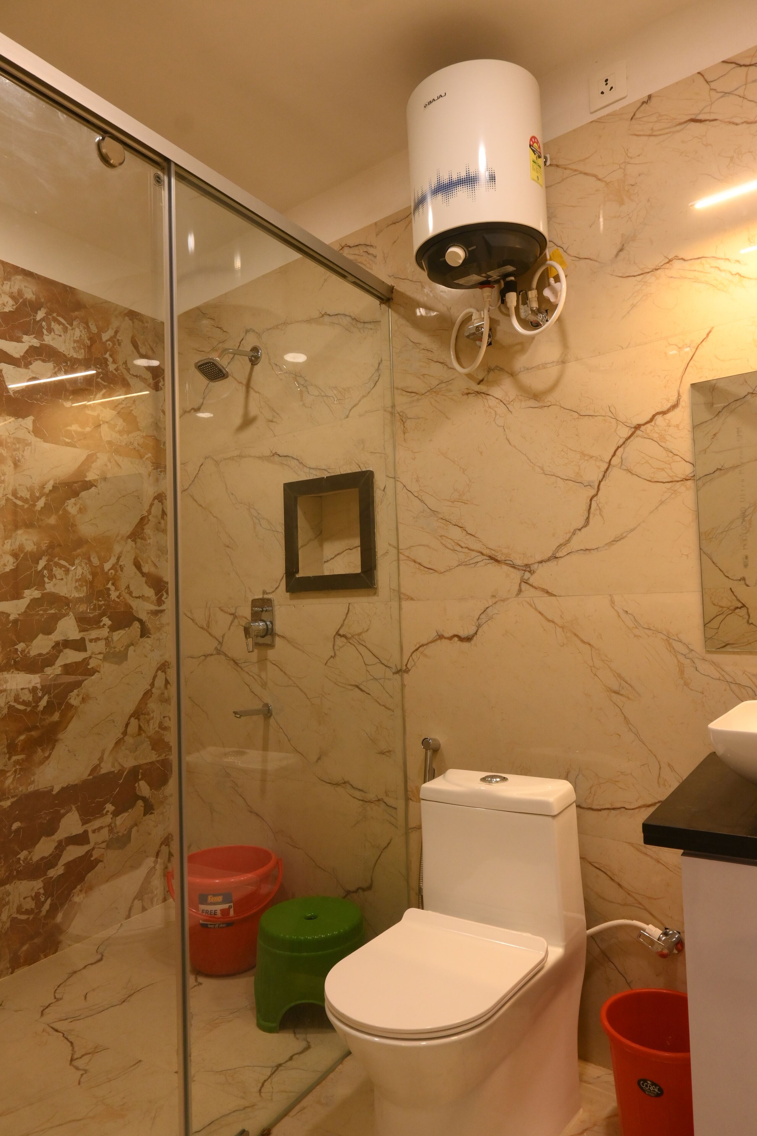 A bathroom with a glass shower enclosure, a toilet, a sink, and a hand dryer.