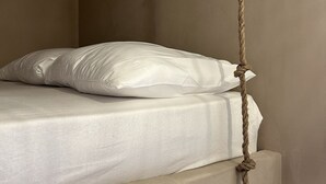 A bed with a white mattress and pillow, a rope tied to the headboard, and a plain wall. - Le Calypso - Magnificent sea-view terrace - 100m from Le Boucanet beach (Le Grau-du-Roi)