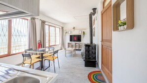 A modern living room with a TV, a fireplace, and a dining area with chairs and a table. - Little Paradise - Lake Lugano View (San Mamete)