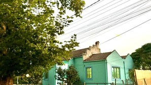Een blauw huis met een duidelijke voordeur en ramen, omringd door een hek en bomen.