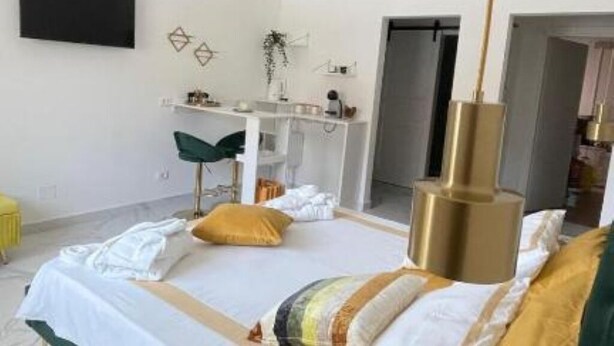Un dormitorio moderno con cama, mesita de noche y televisor montado.