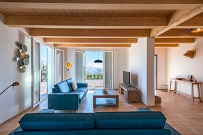 Ein modernes Wohnzimmer mit einer Couch, einem Couchtisch und einem Fernseher. Ein Schiebeglastür führt zu einem Außenbereich.