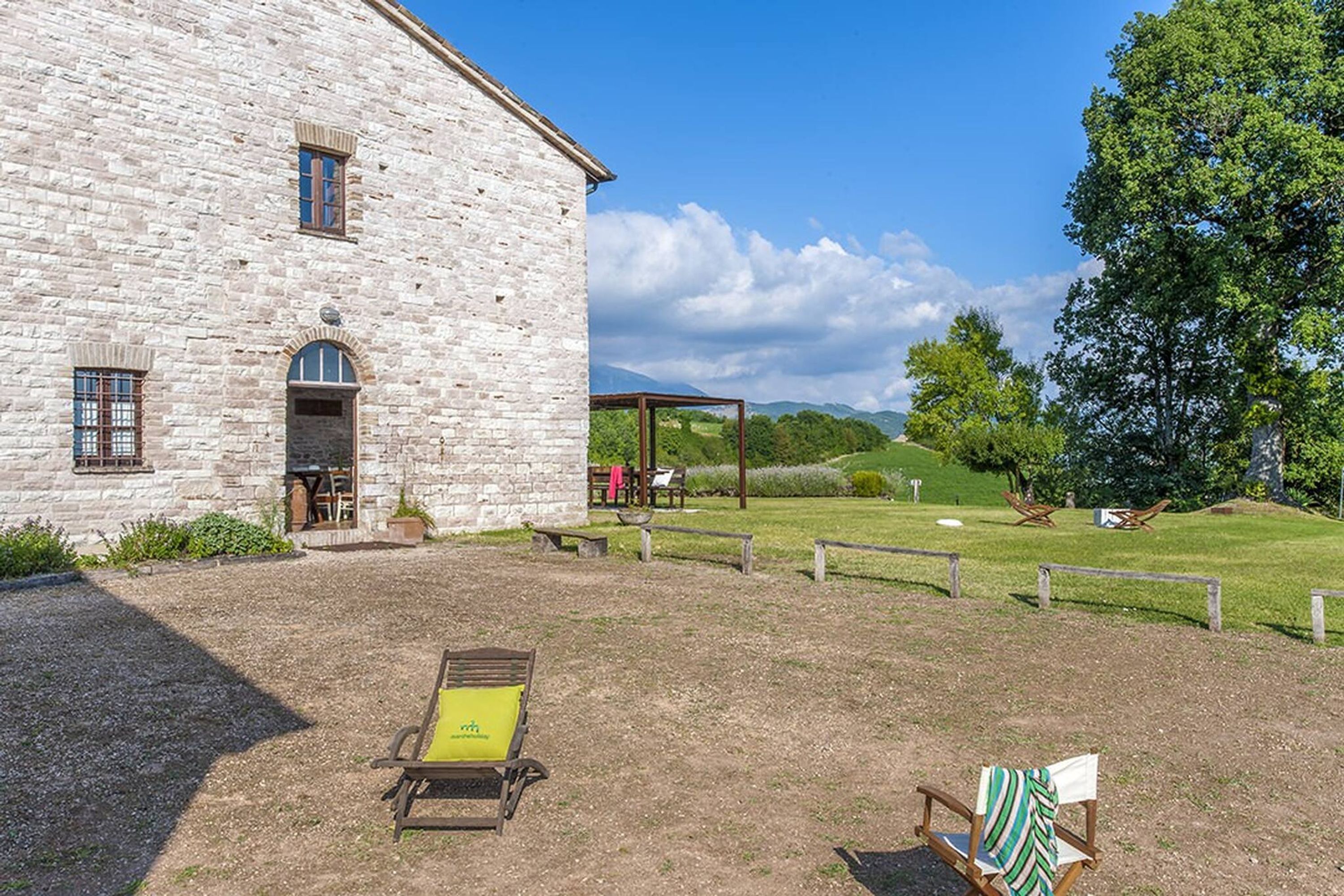 A stone building with a patio area, outdoor seating, and a view of the countryside.