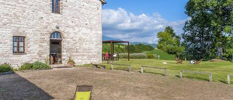 A stone building with a patio area, outdoor seating, and a view of the countryside.