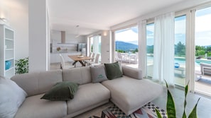 Un salon moderne comprenant un canapé, un coin repas et une vue sur une piscine et des montagnes.
