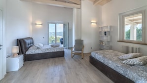 Un dormitorio con dos camas, una silla, una mesita de noche y una ventana con vistas.