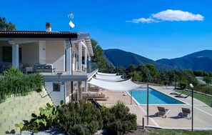 Et moderne hus med pool, udendørs møbler og udsigt til bjerge.