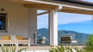 Un balcón con sofá y sillones, con vistas a un paisaje montañoso.