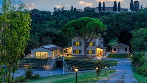Eine moderne Villa mit einer Treppe, die zum Eingang führt, umgeben von üppigem Grün und einem gepflegten Garten.