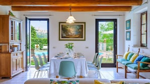 A dining area with a table set for four, a sofa, and a view of the outdoors. - La Girolima 6 2 in Mondavio (Mondavio)