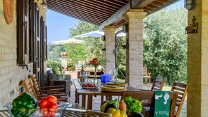 An outdoor patio with a wooden table set for dining, surrounded by chairs, and a grill with vegetables. - La Girolima 6 2 in Mondavio (Mondavio)