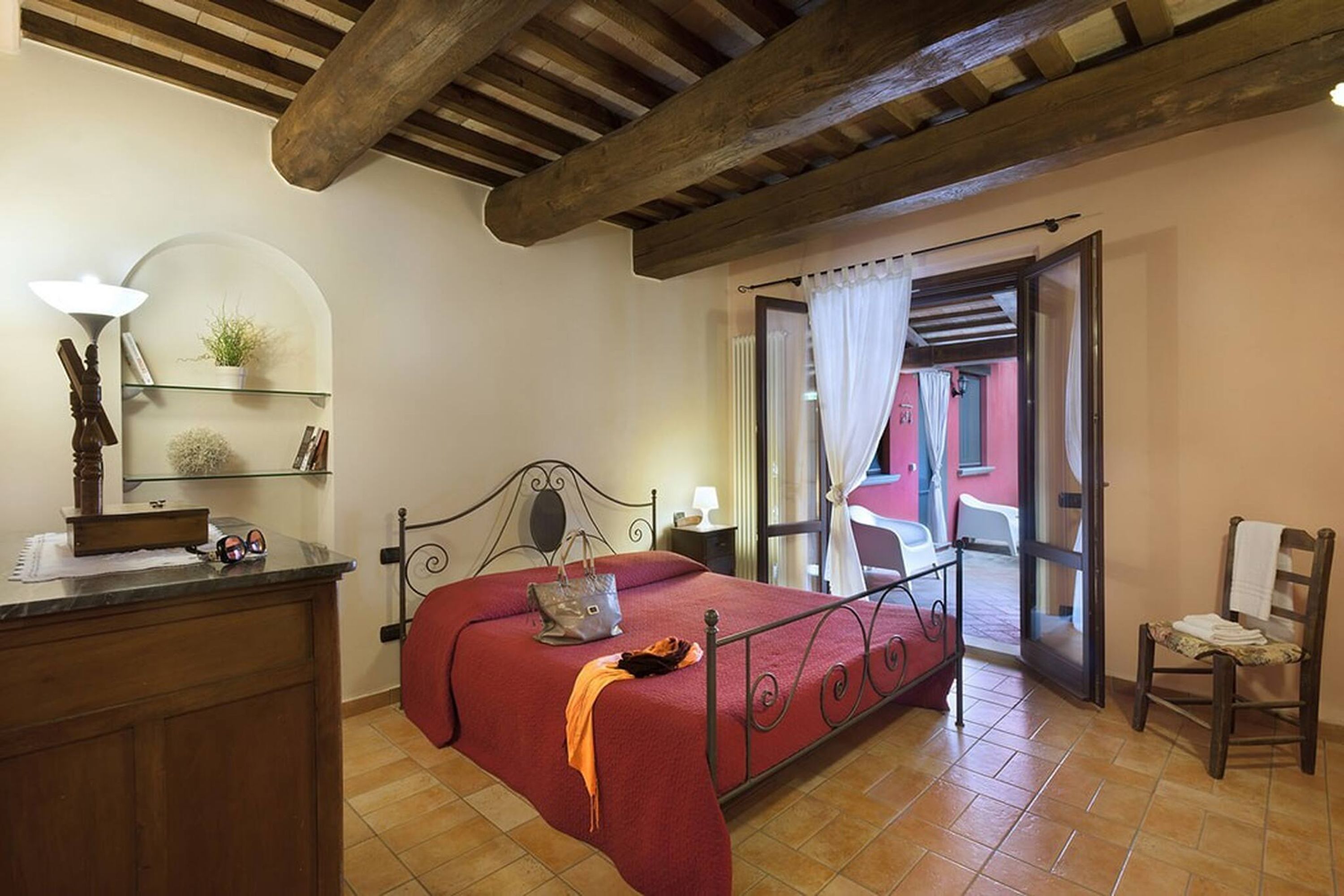 A bedroom with a bed, a desk, a chair, and a window with curtains.