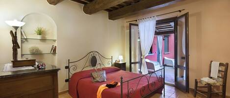 Un dormitorio con cama, escritorio, silla y ventana con cortinas.
