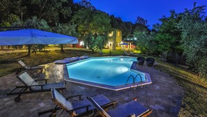 A swimming pool with lounge chairs and umbrellas, surrounded by trees and a house in the background. - Casale Degli Ulivi 8 2 (Acqualagna)