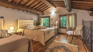 A bedroom with a large bed, a smaller bed, a chair, and a window with curtains. - Casale Degli Ulivi 8 2 (Acqualagna)