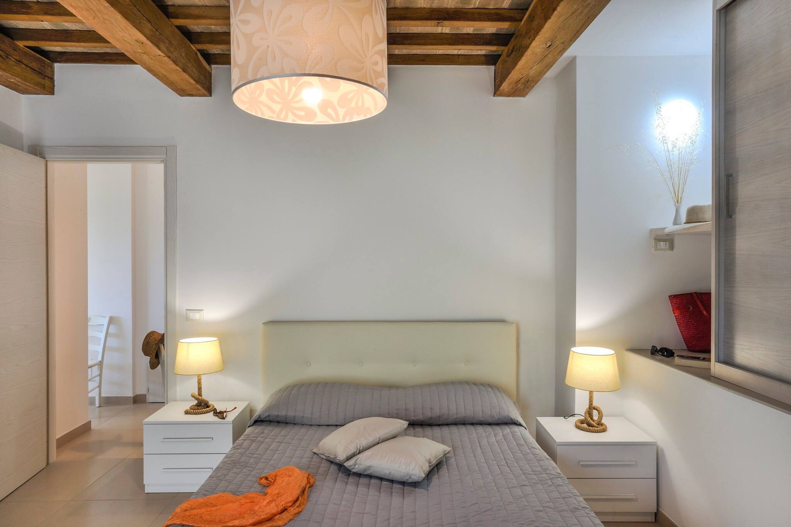 Une chambre à coucher avec un lit, deux tables de chevet avec des lampes, un plafond en bois et une fenêtre donnant sur un beau paysage.