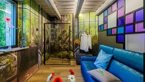 A modern interior with a blue sofa, a glass door leading to a garden, and a wall with colorful square panels. - Casalino Galassi 4 2 (Sarnano)